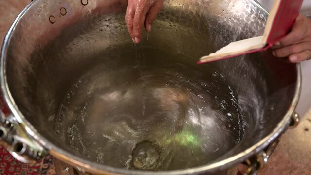 Priest blesses water for baby baptism