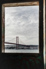 Vertical of a bridge seen through a window on a cloudy day in Ponte, Portugal
