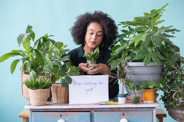 Studio portrait of smiling woman with potted plants and sign