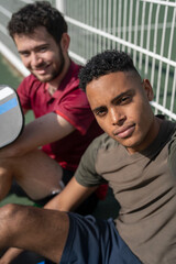 Portrait of two smiling men sitting on pickleball court