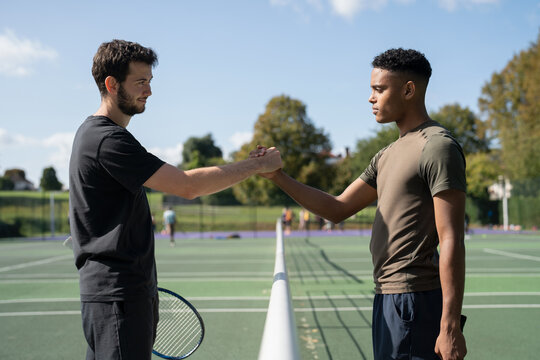 Two men shaking hands in tennis court