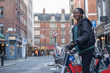 Fototapeta na wymiar Young woman renting city bike