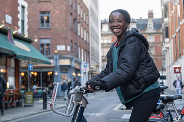 Young woman renting city bike - obrazy, fototapety, plakaty
