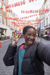 Portrait of happy young woman giving peace symbol in Chinatown