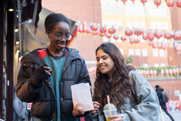 Obraz premium Portrait of two cheerful women with take out food in Chinatown