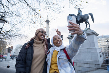 UK, London, Young female tourists in hijabs taking selfie in Trafalgar Square - obrazy, fototapety, plakaty