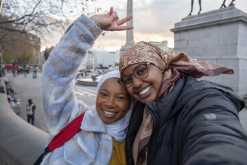 UK, London, Portrait of young female tourists in hijabs in Trafalgar Square - obrazy, fototapety, plakaty