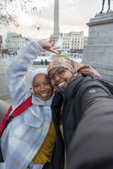 UK, London, Portrait of young female tourists in hijabs in Trafalgar Square