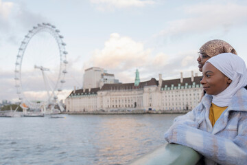 UK, London, Female tourists in hijabs looking at London Eye over River Thames