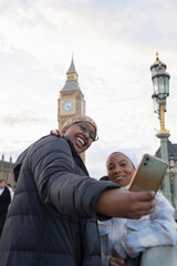 UK, London, Young female tourists in hijabs taking selfie on Westminster Bridge