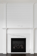 A renovated fireplace detail with shiplap and decorative trim, a white marble slab on the surround,...