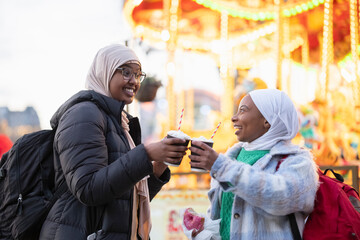 Young female tourists in hijabs having hot cocoa