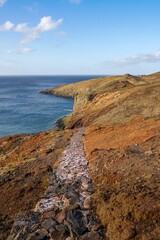 Pathway winds along stony shore.