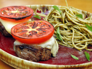 Filet mignon with caprese accompanied by spaghetti with pesto.