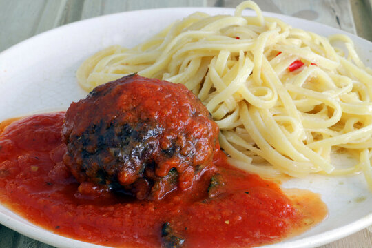 Polpetone in sugo sauce, accompanied by spaghetti with garlic and oil.