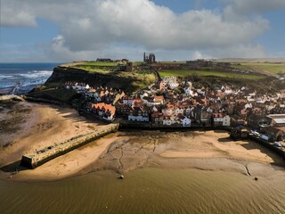 Aerial shot of Whitby town featuring a serene beach coastline with white sandy shoreline