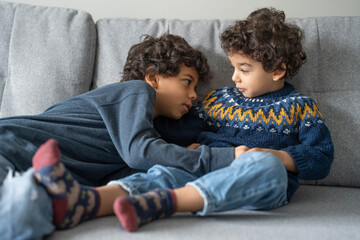 Brothers (2-3, 6-7) relaxing on sofa at home