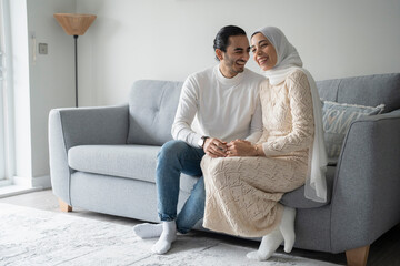 Smiling mid adult couple holding hands on sofa