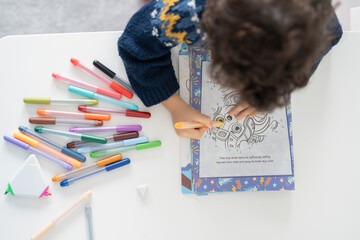 Overhead view of boy (2-3) coloring in coloring book © Cultura Creative