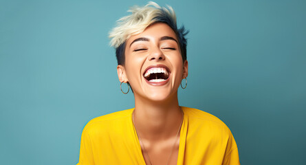 Portrait of a young laughing woman with blond short hairstyle. Isolated over blue background.