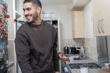 Smiling young man standing in kitchen at home