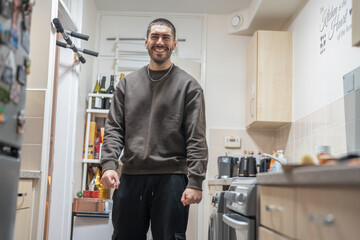 Smiling young man standing in kitchen