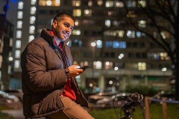 Young man using phone outdoors at night