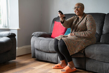Mature woman sitting in living room and watching TV