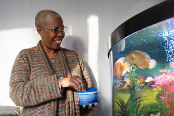 Mature woman feeding fish in aquarium