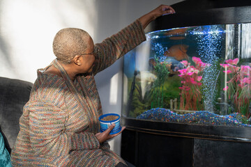 Mature woman feeding fish in aquarium