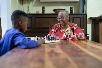 Grandmother and grandson playing chess at home 