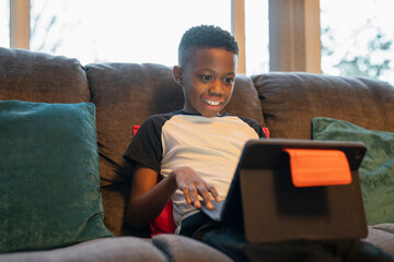Boy with laptop sitting on sofa
