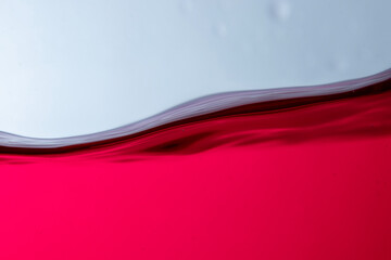 Photograph of juice in a glass jar with water waves. There are bubbles and the background is white.