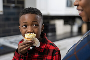 Boy with grandmother tasting fresh baked cupcakes - obrazy, fototapety, plakaty