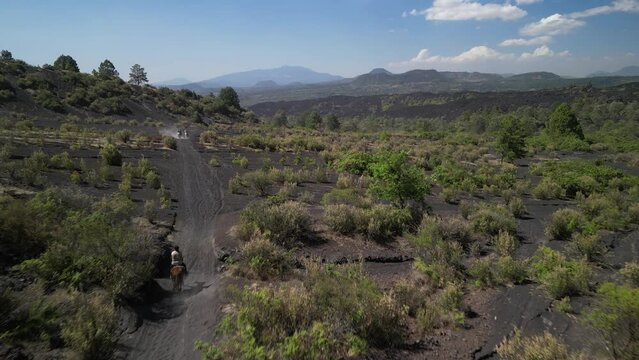 Drone view of people riding horses in volcanic fields near Paricutin volcano in Michoacan, Mexico
