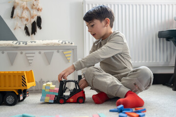 Boy (6-7) sitting on floor and playing with toys © Cultura Creative