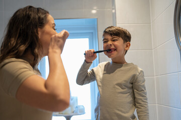 Mother and son (6-7) brushing teeth together