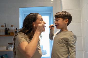 Mother and son (6-7) brushing teeth together