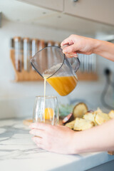 Woman in kitchen, pouring freshly made smoothie