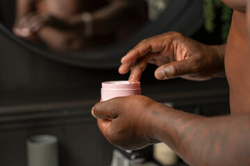 Man taking moisturizer from cream jar