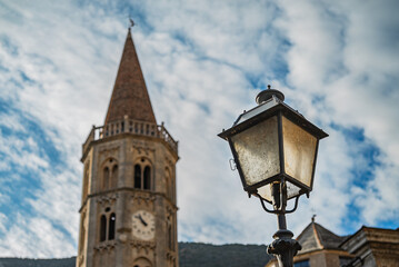 A close up shot of a village of Finalborgo, Finale Ligure, a medieval street lantern(in focus) with an old church(out of focus) on the background and a beautifull cloudy sky, sunset time, Italy 