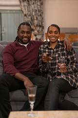 Mid adult couple sitting on sofa and drinking wine