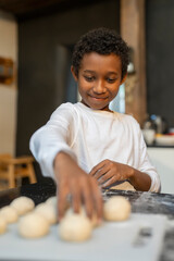 Boy baking cookies in kitchen - obrazy, fototapety, plakaty