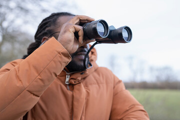 Fototapeta premium Man looking through binoculars in rural area