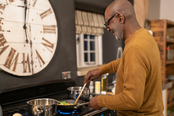 Senior man preparing food in kitchen - obrazy, fototapety, plakaty