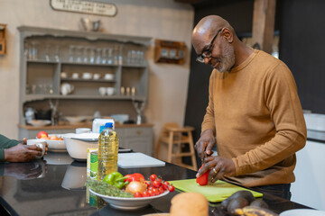 Senior man preparing meal in kitchen - obrazy, fototapety, plakaty