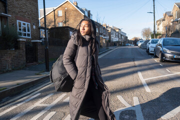 Portrait of woman in long overcoat crossing street