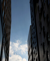 Modern buildings with blue sky, contrast between bright clouds and shadowed buildings