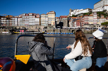 Fototapeta na wymiar View of Cais da Ribeira in O Porto on a sunny day from a tourist boat with tourists