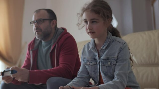 Father and Daughter Expressing Emotions While Enjoying Relaxing Together, Playing Video Games in Front of TV. Family Time Hobby. Family Having Fun Together at Home in Living Room Playing Video Games.